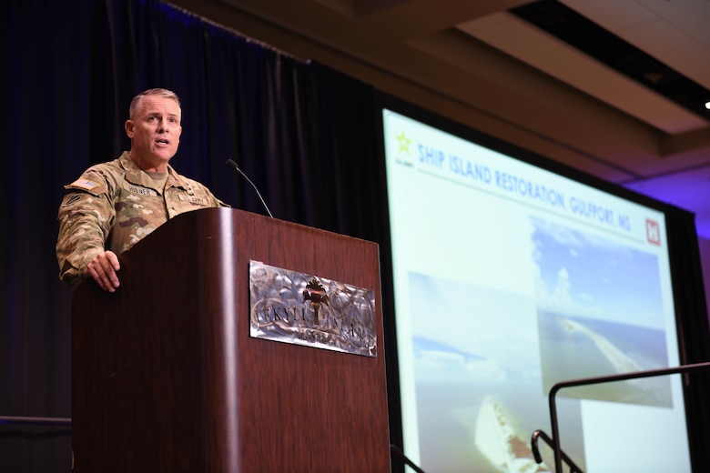 Photo of USACE Commander standing behind a podium presenting a slide presentation.