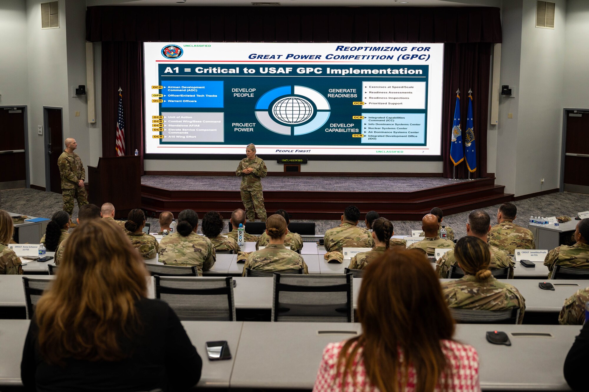 Woman briefs a room full of Airmen