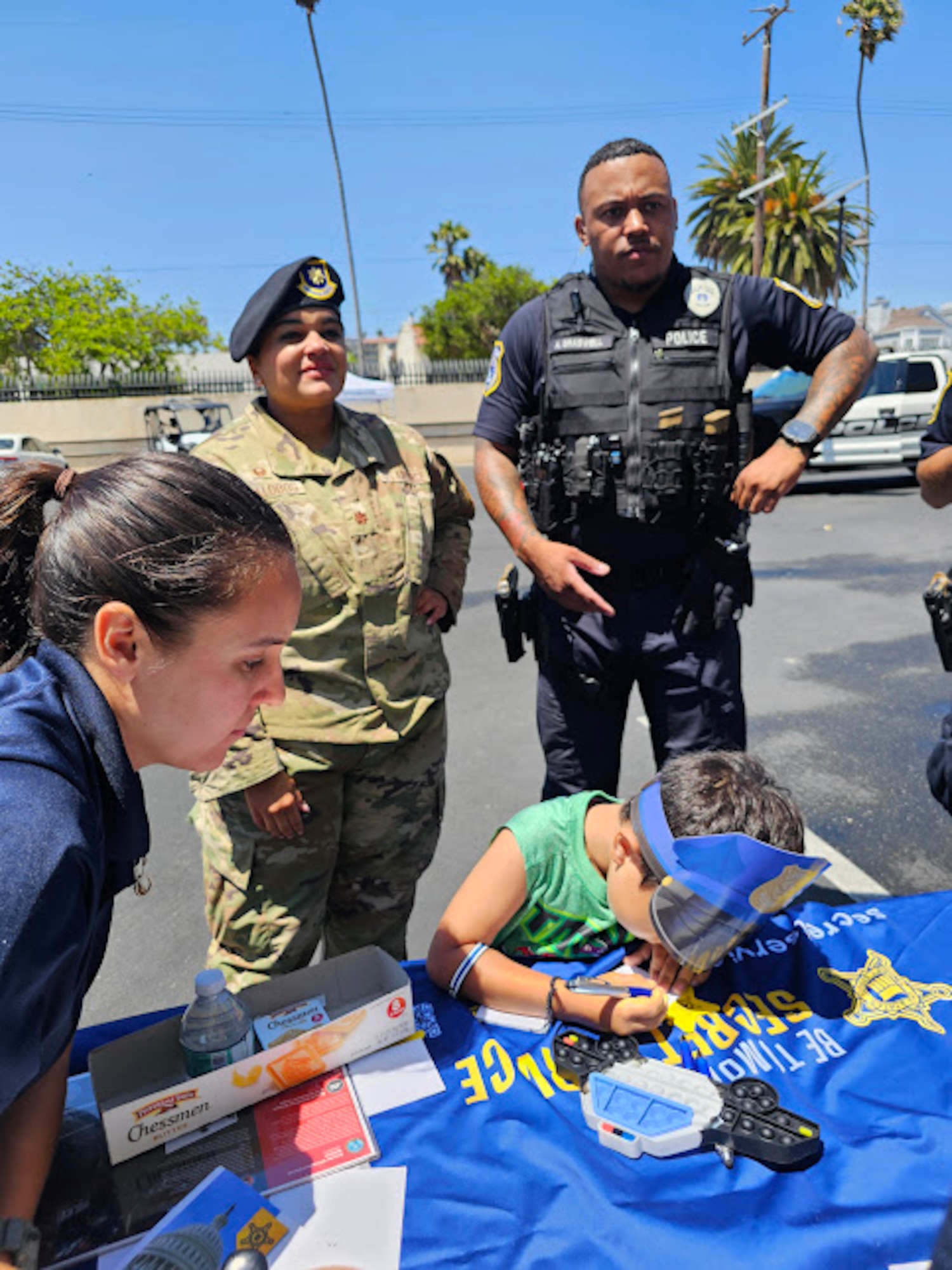 A military child checks out the Secret Service booth, as civilian and military police chat.