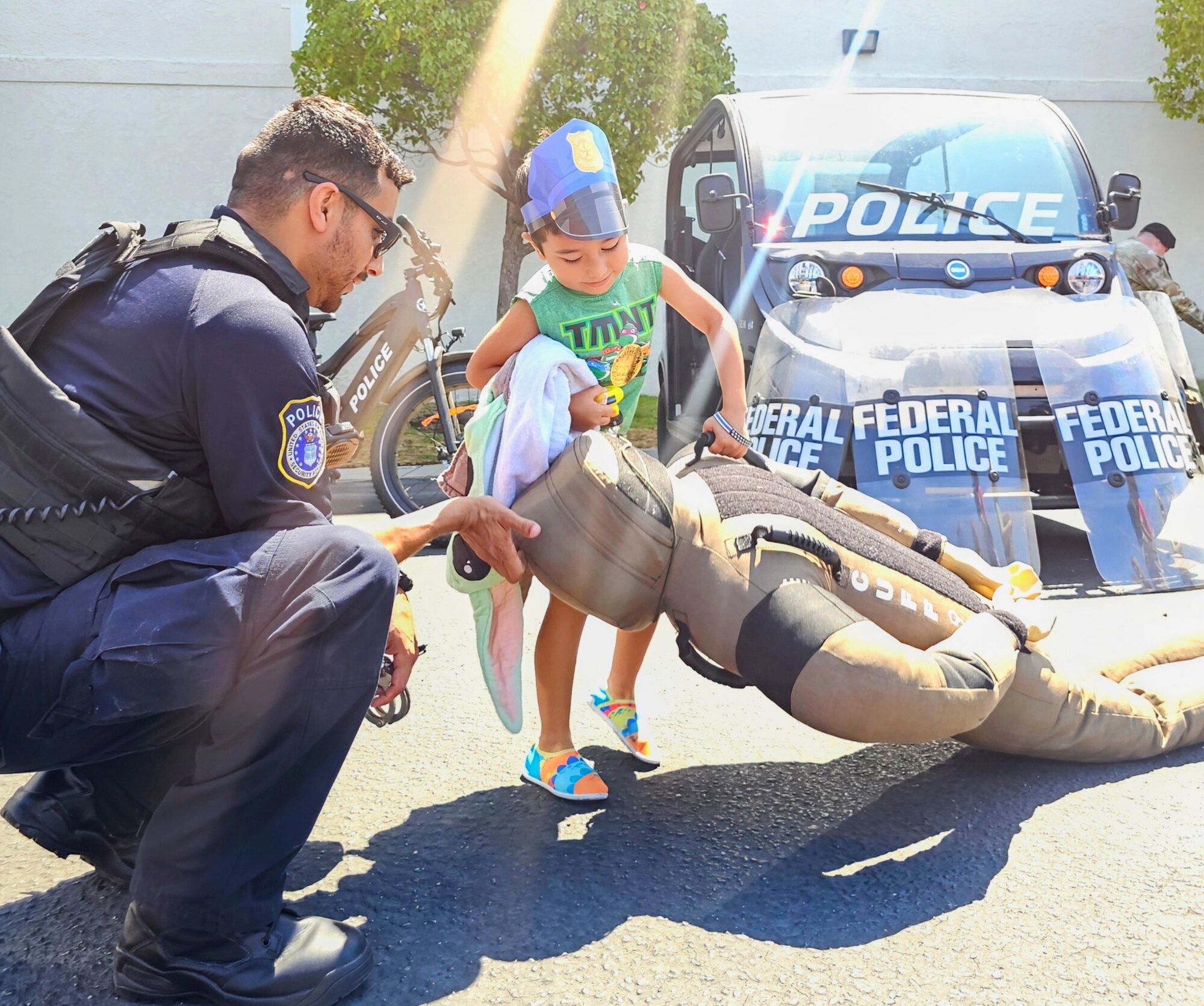 A Department of the Air Force Civilian Police Officer helped a military child check out training equipment at, “Empowering Military Youth Day,”
