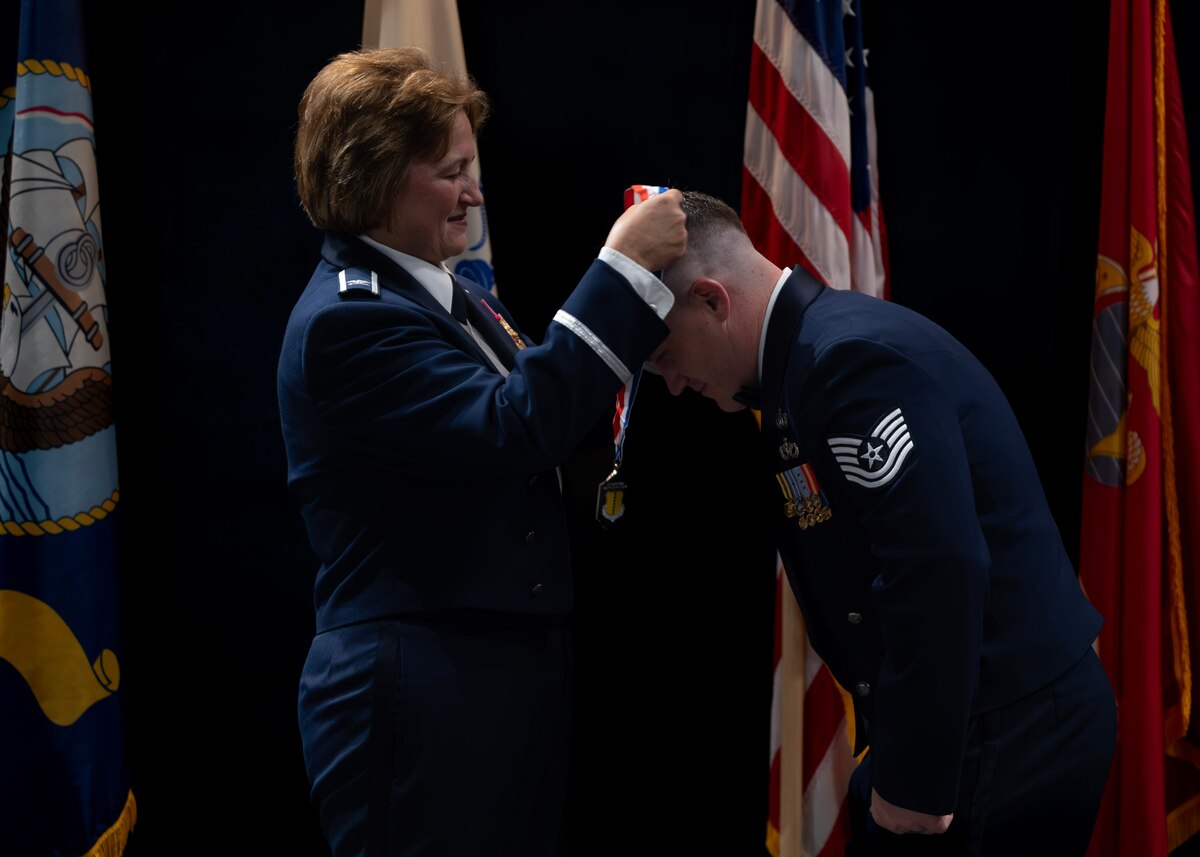 U.S. Air Force Col. Angelina Maguinness, 17th Training Wing commander, bestows Master Sgt. Select Cody West, 17th Civil Engineer Squadron senior enlisted leader, a Master Sgt. medal to Tech. Sgt., before the Senior Noncommissioned Officer Induction Ceremony at the Powell Event Center, Goodfellow Air Force Base, Texas, Aug. 23, 2024. Some of the primary leadership duties of SNCOs are to be superintendents, supervisors, or managers of flights, functions, or activities. (U.S. Air Force photo by Senior Airman Sarah Williams)