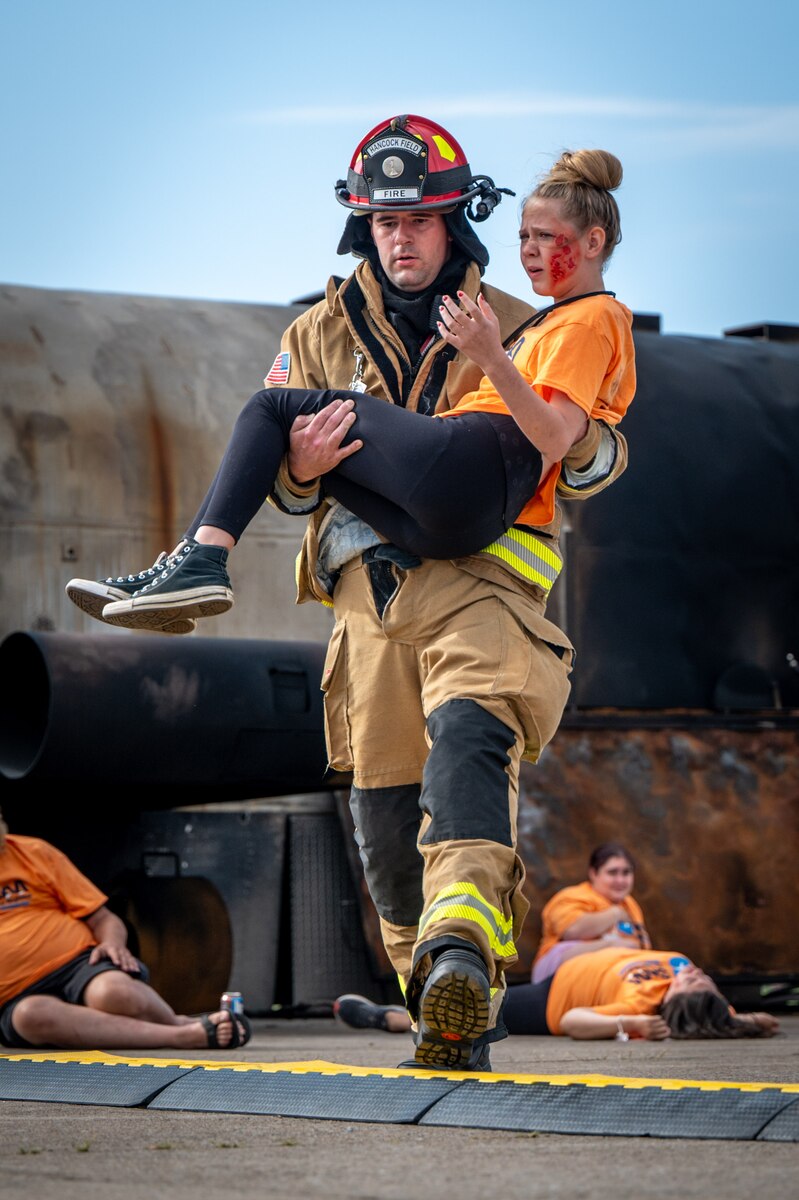 Justin Stacy, A lead firefighter assigned to the Hancock Field Air National Guard Base fire department, carries a role-player to safety while participating in a disaster drill at Syracuse Hancock International Airport, Aug. 10.