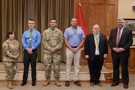 Brig. Gen. Laura McHugh, left, deputy adjutant general-Army, Pennsylvania National Guard, and retired Col. Richard Spiegel, right, of the Army Public Affairs Association, pose with members of the Pennsylvania National Guard state public affairs office after presenting them with the U.S. Army Keith L. Ware Public Affairs Organization of the Year award and Order of Saint Gabriel medallions during a ceremony Aug. 20, 2024, at Fort Indiantown Gap, Pennsylvania. (U.S. Army National Guard photo by Spc. Jessica Barb)