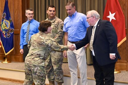 Brig. Gen. Laura McHugh, deputy adjutant general-Army, Pennsylvania National Guard, congratulates Wayne V. Hall, state public affairs officer, after presenting the members of the state public affairs office with the U.S. Army Keith L. Ware Public Affairs Organization of the Year award Aug. 20,2024, at Fort Indiantown Gap. (U.S. Army National Guard photo by Spc. Jessica Barb)