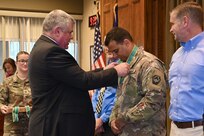 Retired Col. Richard Spiegel, of the Army Public Affairs Association, presents an Order of Saint Gabriel medallion to Maj. Travis Mueller, media operations officer, during a ceremony Aug. 20, 2024, at Fort Indiantown Gap, Pennsylvania. (U.S. Army National Guard photo by Spc. Jessica Barb)