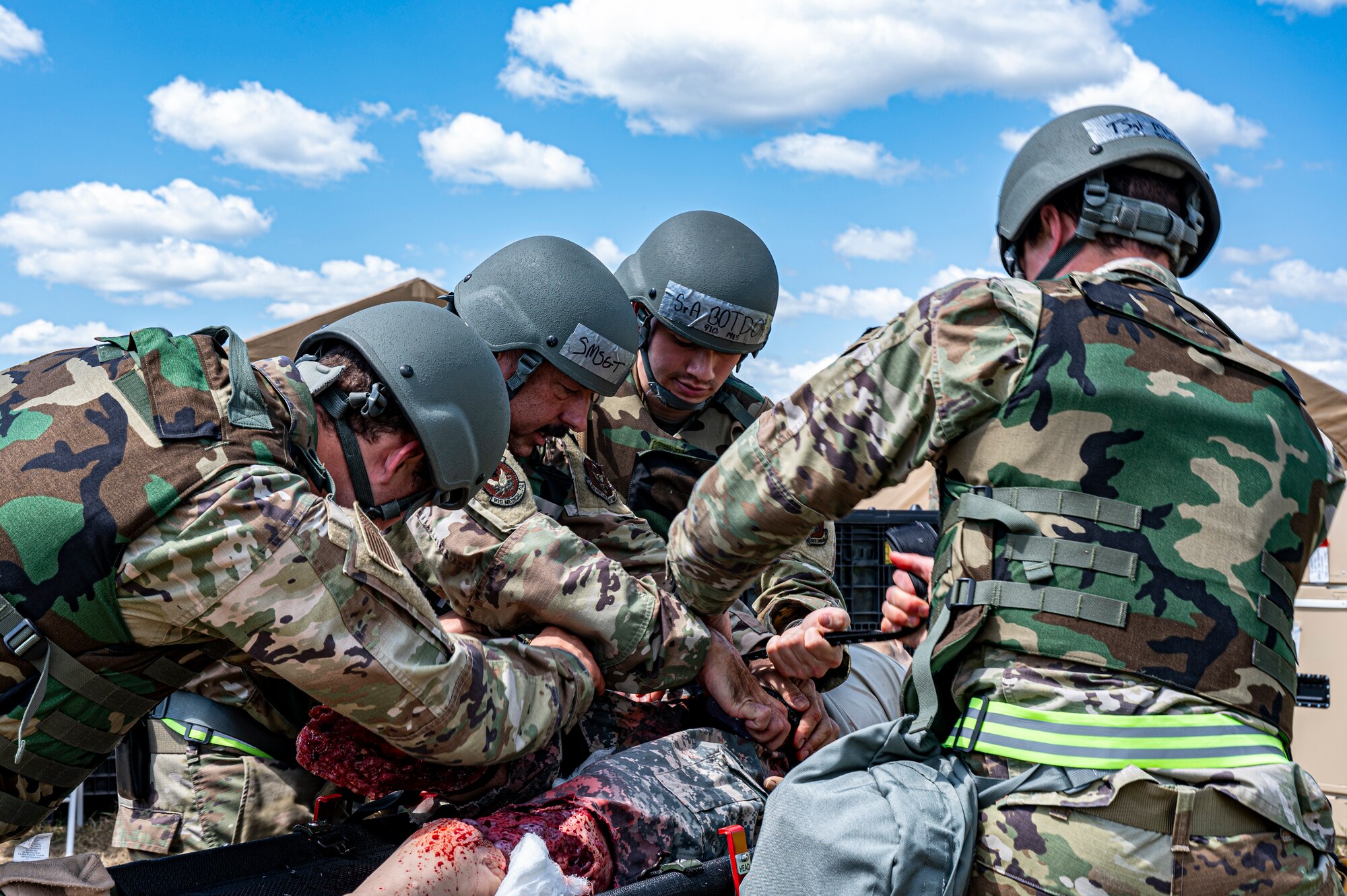 Four Air Force Reserve medics surround a simulated patient casualty outside an Expeditionary Medical Support facility.