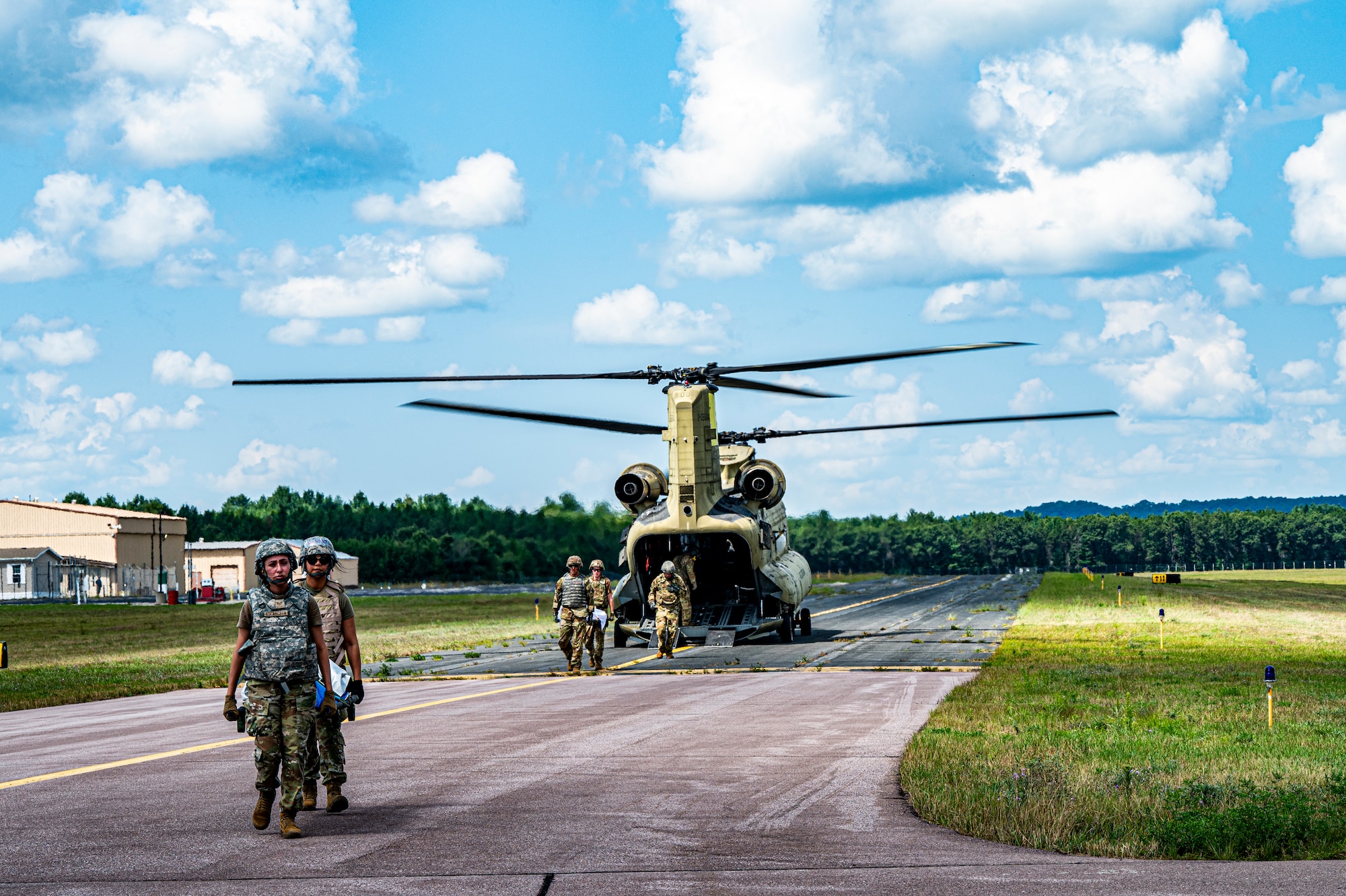 Air Force Reserve medics carry litters of simulated patients from a Chinook helicopter as its propellers spin on the Fort McCoy Sparta Airfield.