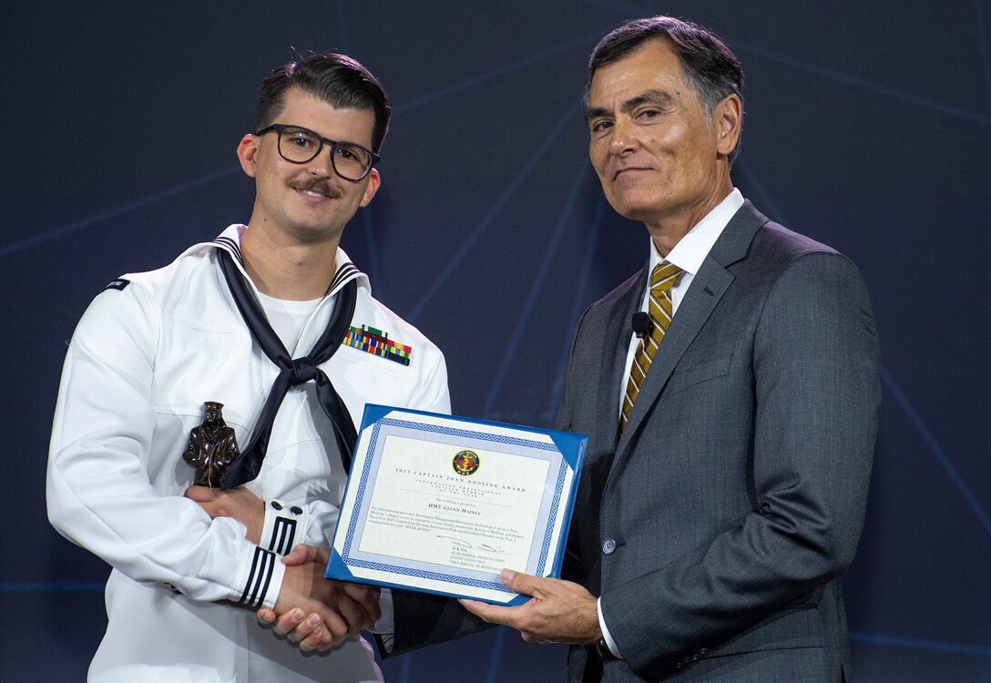 U.S. Navy Hospital Corpsman 2nd Class Glenn Hainey, assigned to Navy Medicine Training Support Center, is presented the 2023 Capt. Joan Dooling Award “Information Professional Enlisted Member of the Year” by Dr. Michael McGinnis, the executive director for U.S. Navy Bureau of Medicine and Surgery, at the 2024 Defense Health Information Technology Symposium in Dallas, Texas, Aug. 20, 2024. The Dooling Award is the ultimate recognition of professional achievement and accomplishment for deserving members of the Navy Medicine Enterprise information management and information technology community.