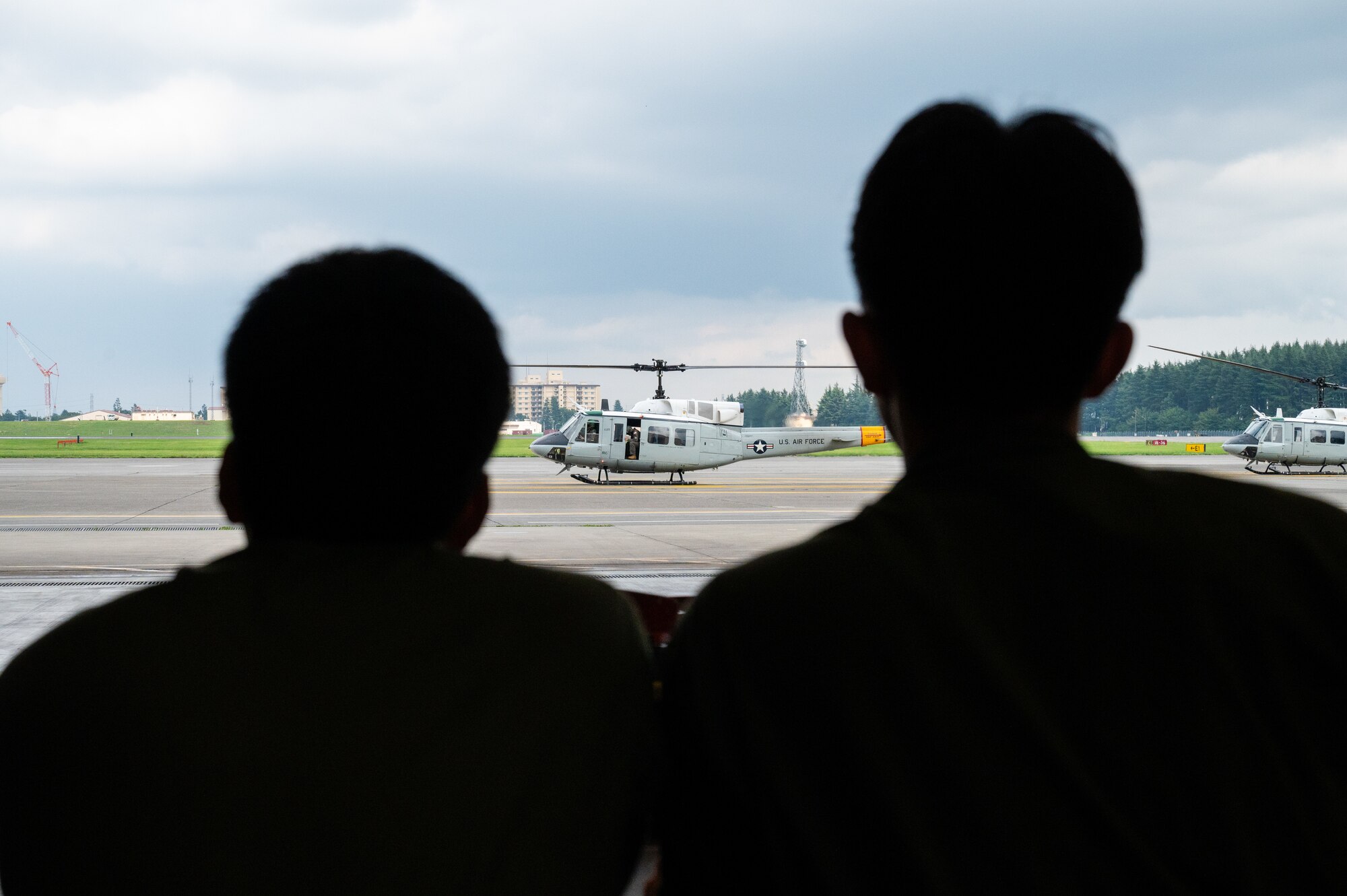 Japan Air Self-Defense Force Officer Candidate School students watch as a UH-1N Huey assigned to the 459th Airlift Squadron prepares for takeoff during a tour at Yokota Air Base, Japan.