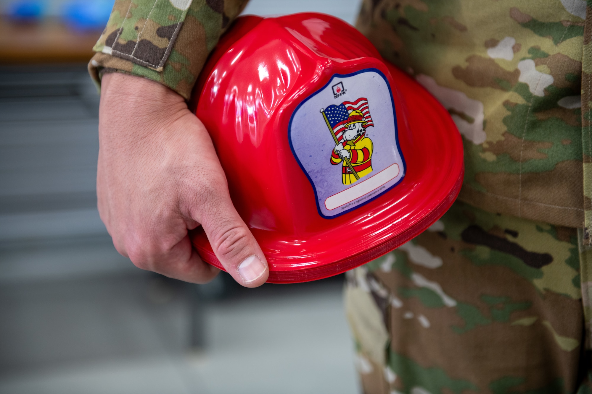 A U.S. servicemember holds a stack of plastic firefighter helmets used to distribute during the Tokyo Fire Prevention Week event.