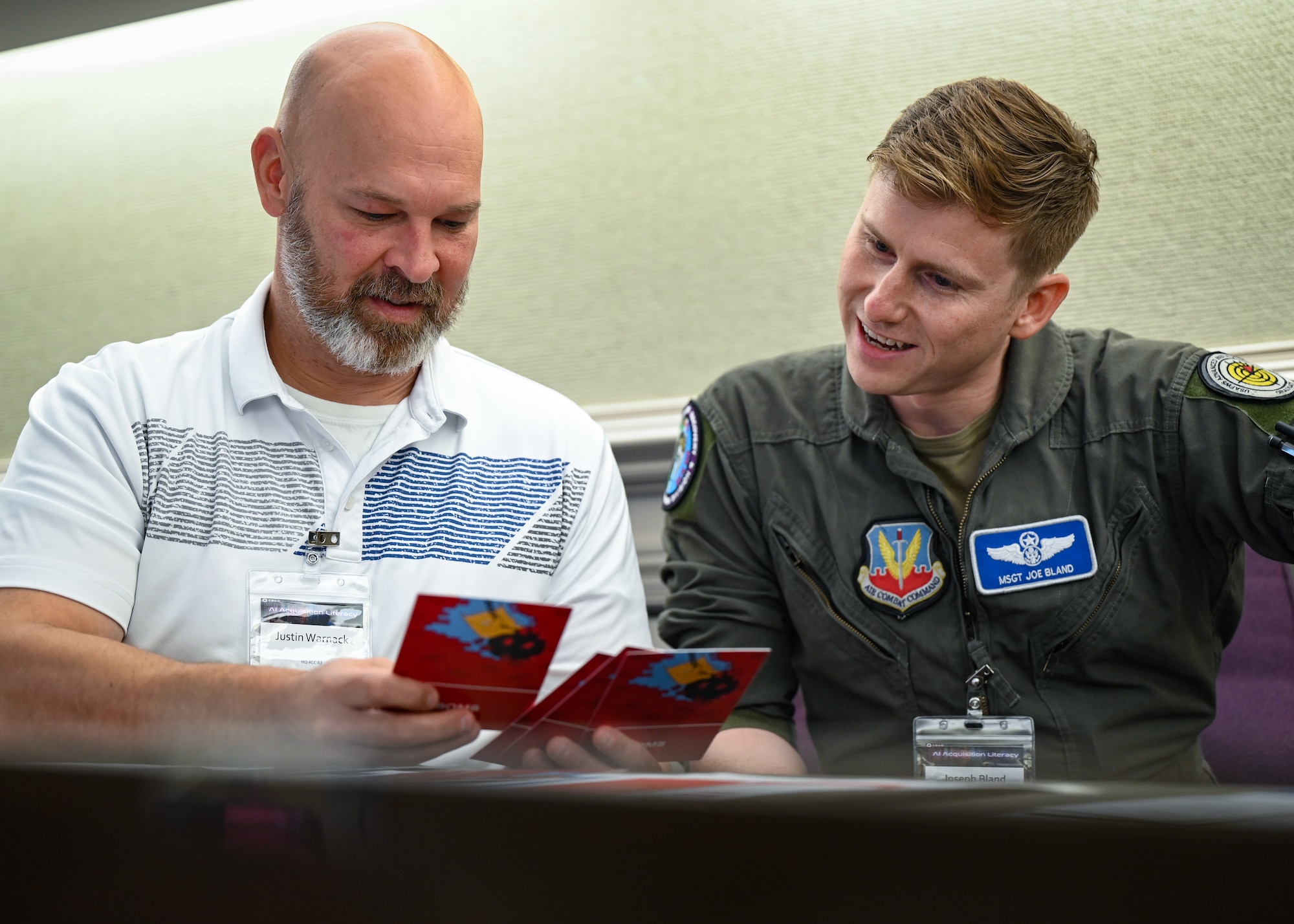 Justin Warnack (left), Air Combat Command participant, and U.S. Air Force Master Sgt. Joseph Bland (right), ACC participant, review game cards during a ‘debate’ exercise during an Artificial Intelligence acquisition literacy course