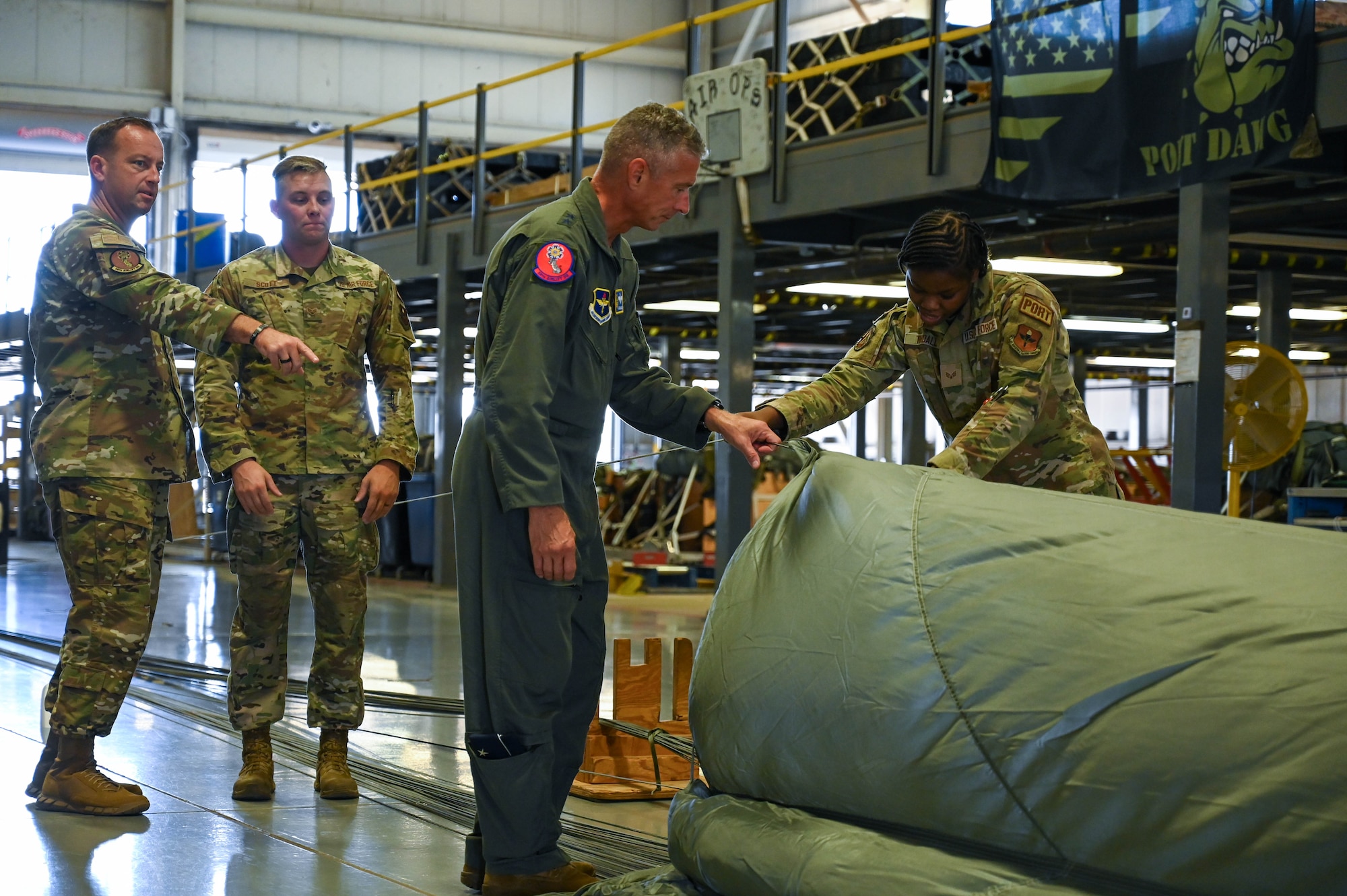 U.S. Air Force Senior Airman Shanice Tindall, 97th Logistics Readiness Squadron (LRS) unilateral aircrew training rigger, right, inflates a parachute with the 19th Air Force (AF) command team at Altus Air Force Base, Oklahoma, Aug. 23, 2024. The 19th AF command team met with Airmen from the 97th LRS to experience what they do on a day-to-day basis and offer guidance and mentorship for being successful as operations Airmen in the Air Force. (U.S. Air Force photo by Airman 1st Class Heidi Bucins)