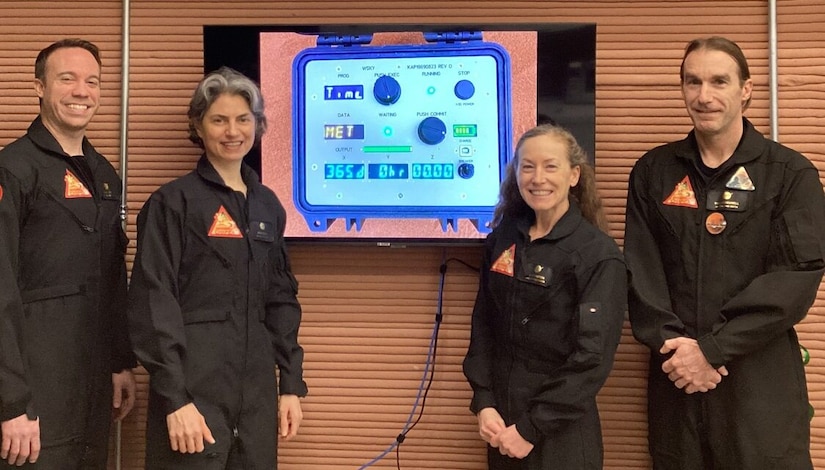 Four people stand beside a screen with a countdown clock.