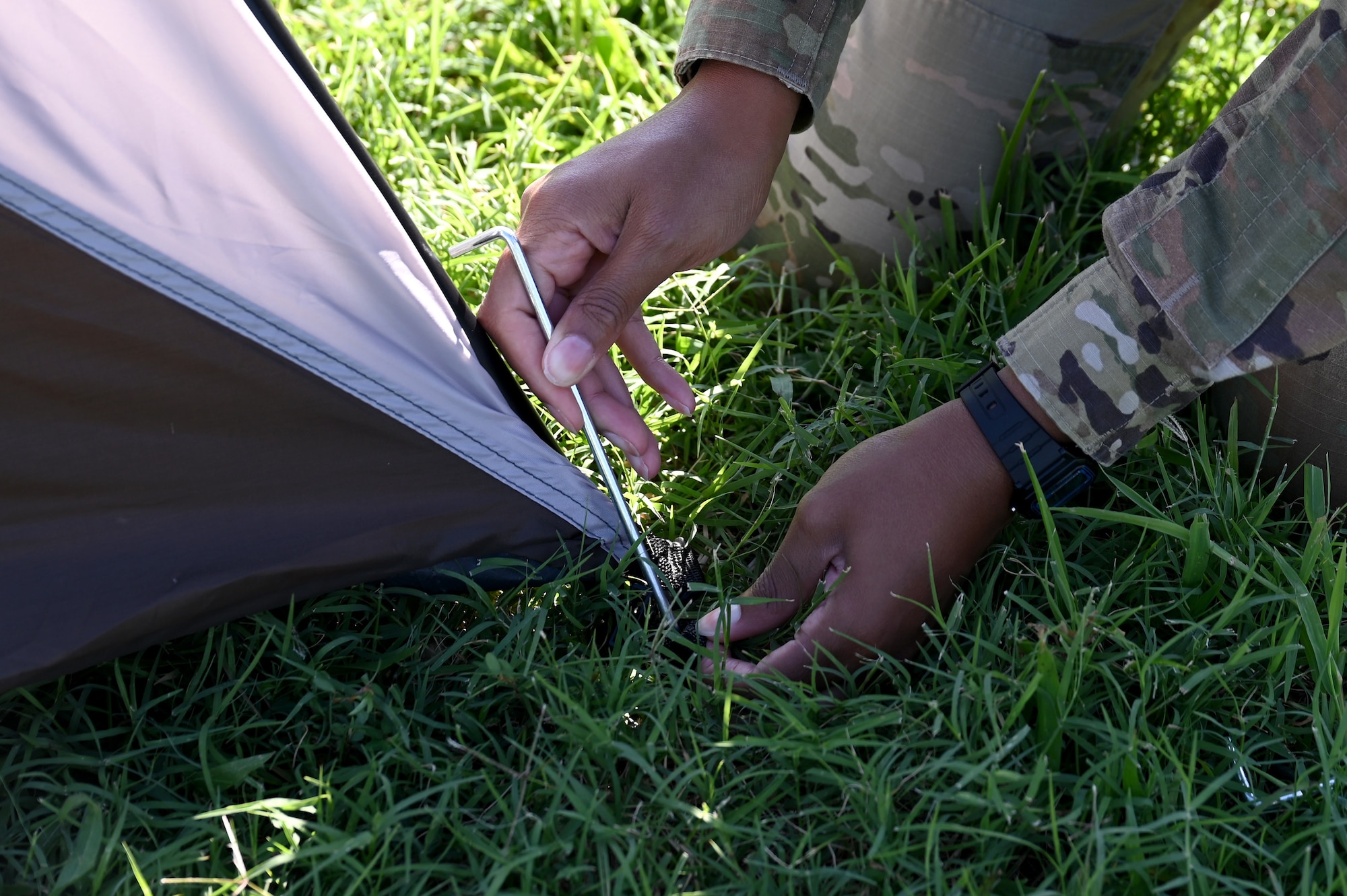 A U.S. Airman secures a tent with a stake during a demonstration of the fourth iteration Deployed Intelligence Combat Element kit at Joint Base Langley-Eustis, Virginia, Aug. 22, 2024. The DICE-4 kit allows intelligence analysts to rapidly deploy to any location with the capability of setting up a Sensitive Compartmented Information Facility in minutes. (U.S. Air Force photo by Staff Sgt. Kelsey Owen)
