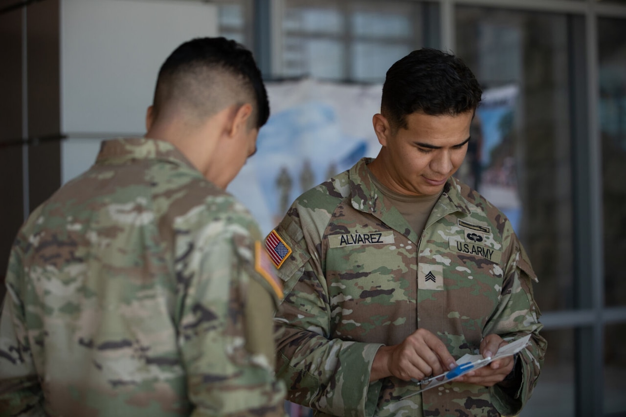 Two men in military uniform look down at paperwork.