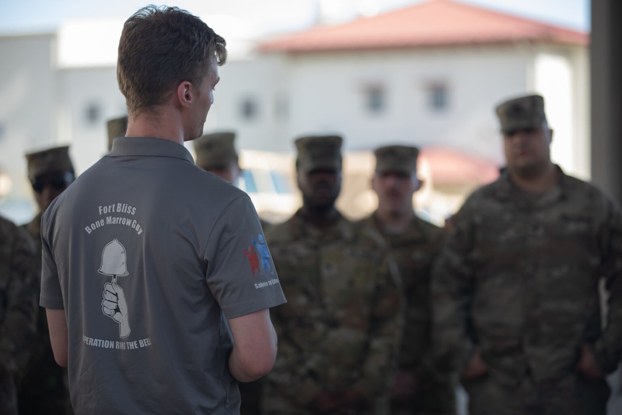 A man talks to a group of service members.