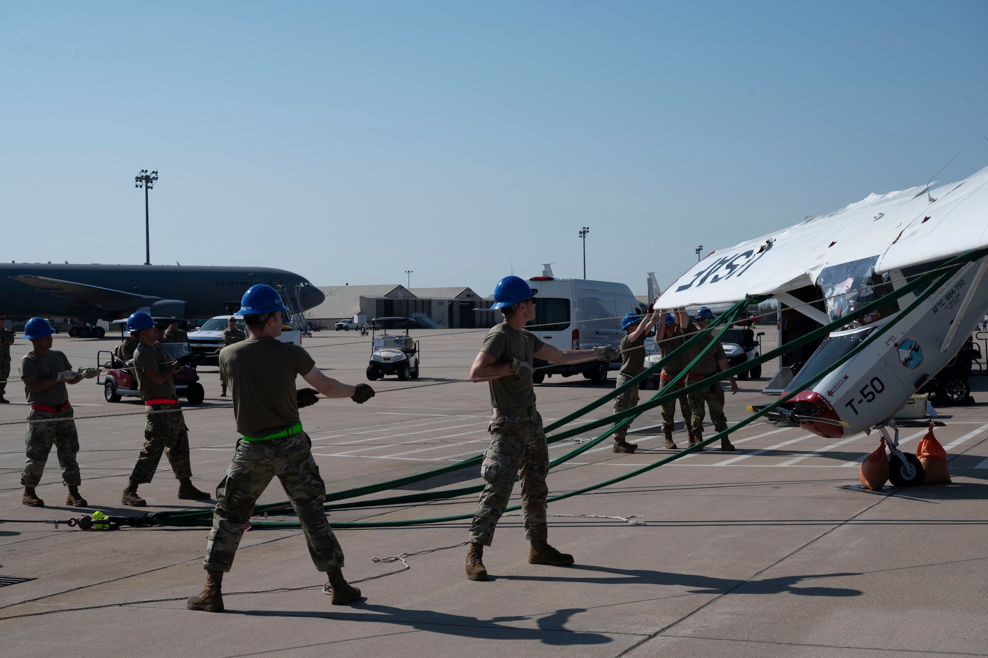Airmen from the 22nd Aircraft Maintenance Squadron Crash Damage or Disabled Aircraft Recovery team work together to maneuver a flipped aircraft right side up Aug. 26, 2024, at McConnell Air Force Base, Kansas. The aircraft was flipped during a thunderstorm with wind gusts of up to 54 mph on Aug. 25, 2024. The storm caused damage to several visiting aircraft and vendor stands leading to the cancelation of the second day of the Frontiers in Flight Airshow. (U.S. Air Force photo by Airman 1st Class Gavin Hameed)