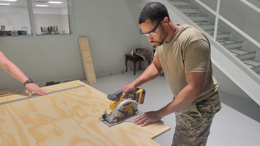 Airman sawing plywood