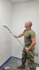 Airman painting a wall with a paint roller