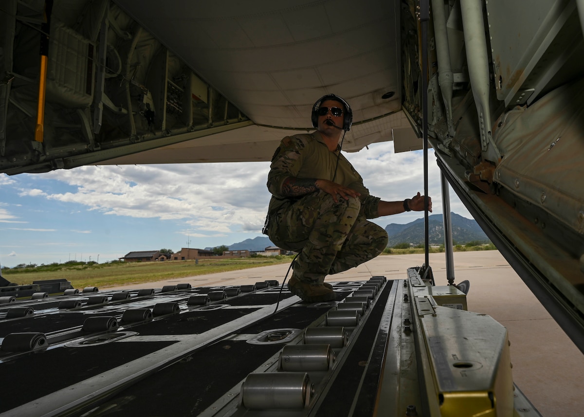 A man in a military uniform stands on the back of a plane