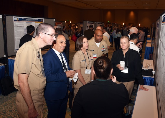 KISSIMMEE, Fla. – (Aug. 27, 2024) – Meaghan Rose, a research scientist assigned to Craniofacial Health and Restorative Medicine Directorate, Naval Medical Research Unit (NAMRU) San Antonio, briefs research titled “Effects of Heat and Humidity on the Physical and Biological Properties of Endodontic Sealers in Simulated Military Storage and Transit Conditions” to Naval Medical Research Command (NMRC) and NAMRU San Antonio leadership during Poster Session One on day two of the 2024 Military Health System Research Symposium (MHSRS) held at the Gaylord Palms Resort and Convention Center. The MHSRS brings together military, government, academia, and industry experts for four days of critical conversations and intensive idea sharing. Presenters will share their latest research findings and challenges on topics including combat casualty care, military operational medicine, clinical and rehabilitative medicine, medical simulation and information sciences, military infectious diseases, and the radiation health effects. NAMRU San Antonio is one of the leading research and development laboratories for the U.S. Navy under the Department of Defense (DoD) and is one of eight subordinate research commands in the global network of laboratories operating under the Naval Medical Research Command in Silver Spring, Md.  Its mission is to conduct gap driven combat casualty care, craniofacial, and directed energy research to improve survival, operational readiness, and safety of DoD personnel engaged in routine and expeditionary operations. (U.S. Navy photo by Burrell Parmer, NAMRU San Antonio Public Affairs/Released)