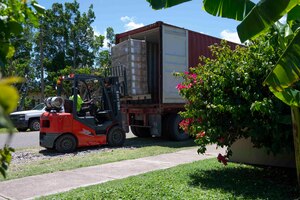 A photo of a forklift moving boxes from inside a truck.