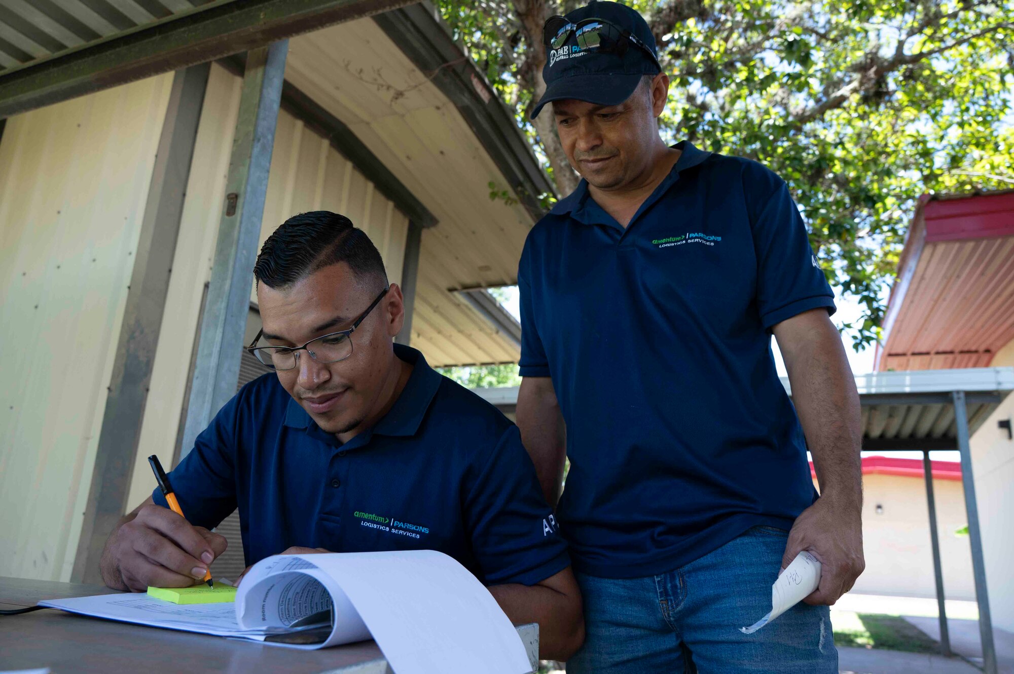 A photo of two people looking at a paper while one is writing something down.