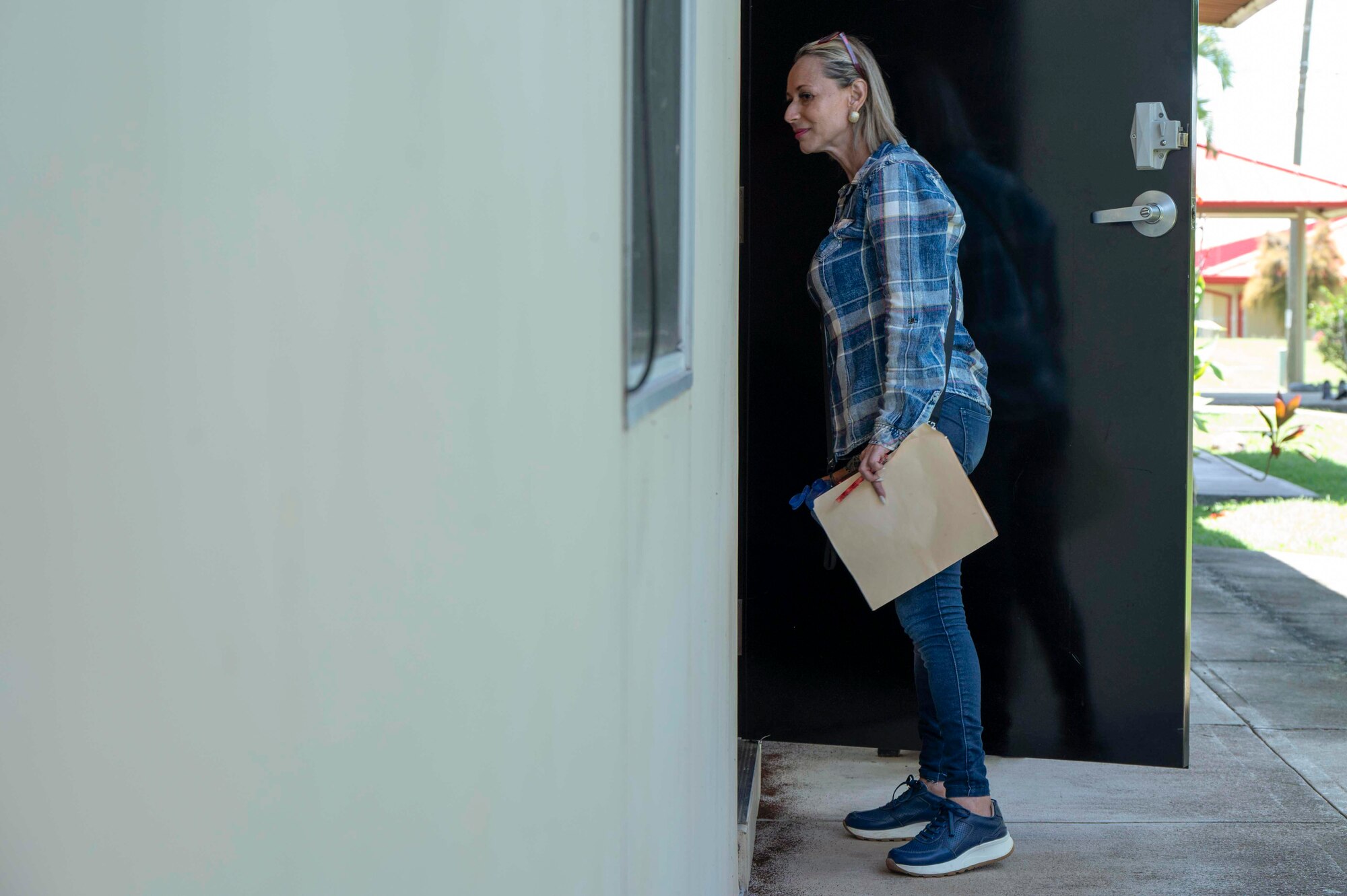 A photo of a woman peeking inside a door of a room.