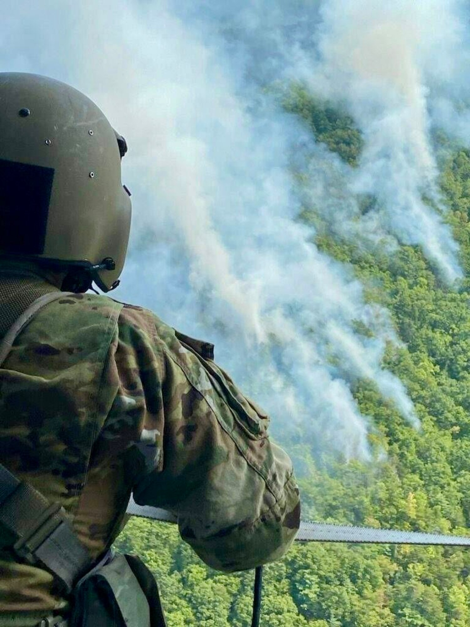A Tennessee National Guard UH-60 Black Hawk helicopter crew chief from Knoxville’s 1-230th Assault Helicopter Battalion monitors wildfires in Great Smoky Mountains National Park, Aug. 27, 2024. The Guard dropped thousands of gallons of water on the fires from the air.