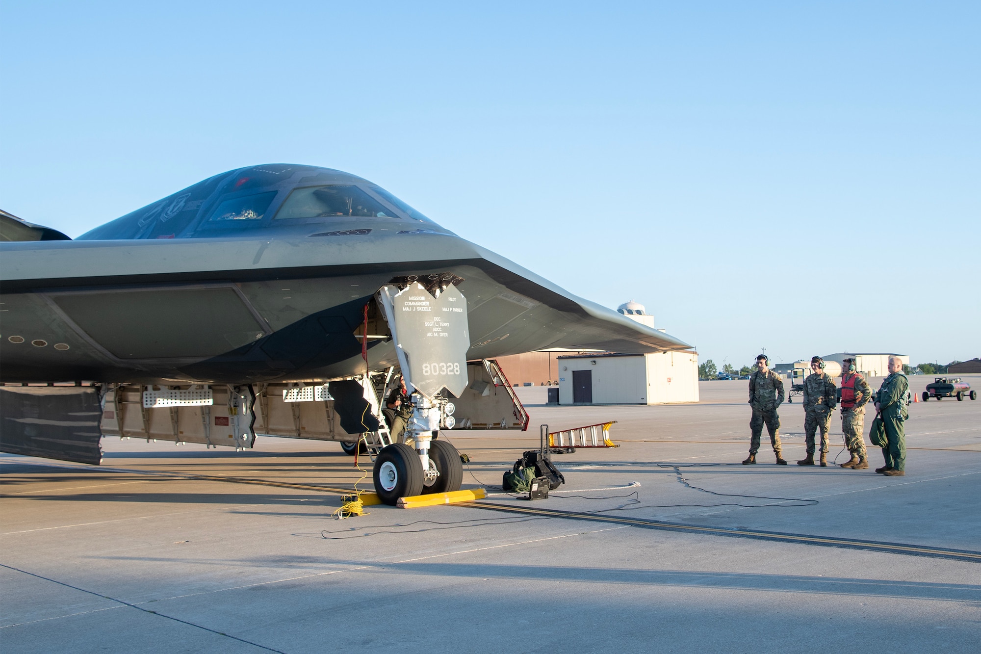 U.S. Air Force Airmen stand near a B-2 Spirit stealth bomber on the flight line at Whiteman Air Force Base.
