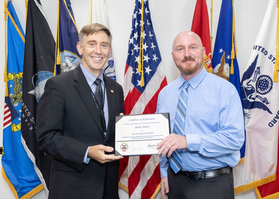 A man hands another man a certificate.