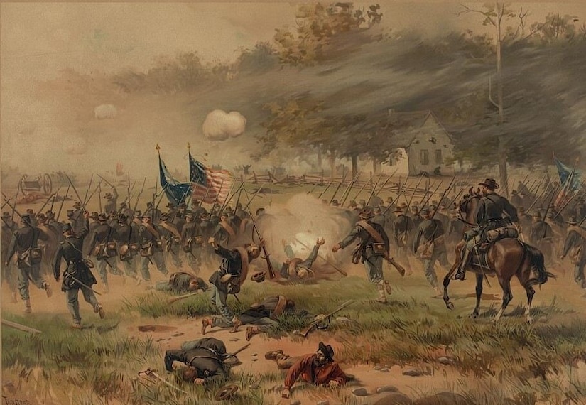 Hundreds of men on horses and on foot run across a battlefield with the U.S. flag unfurled.