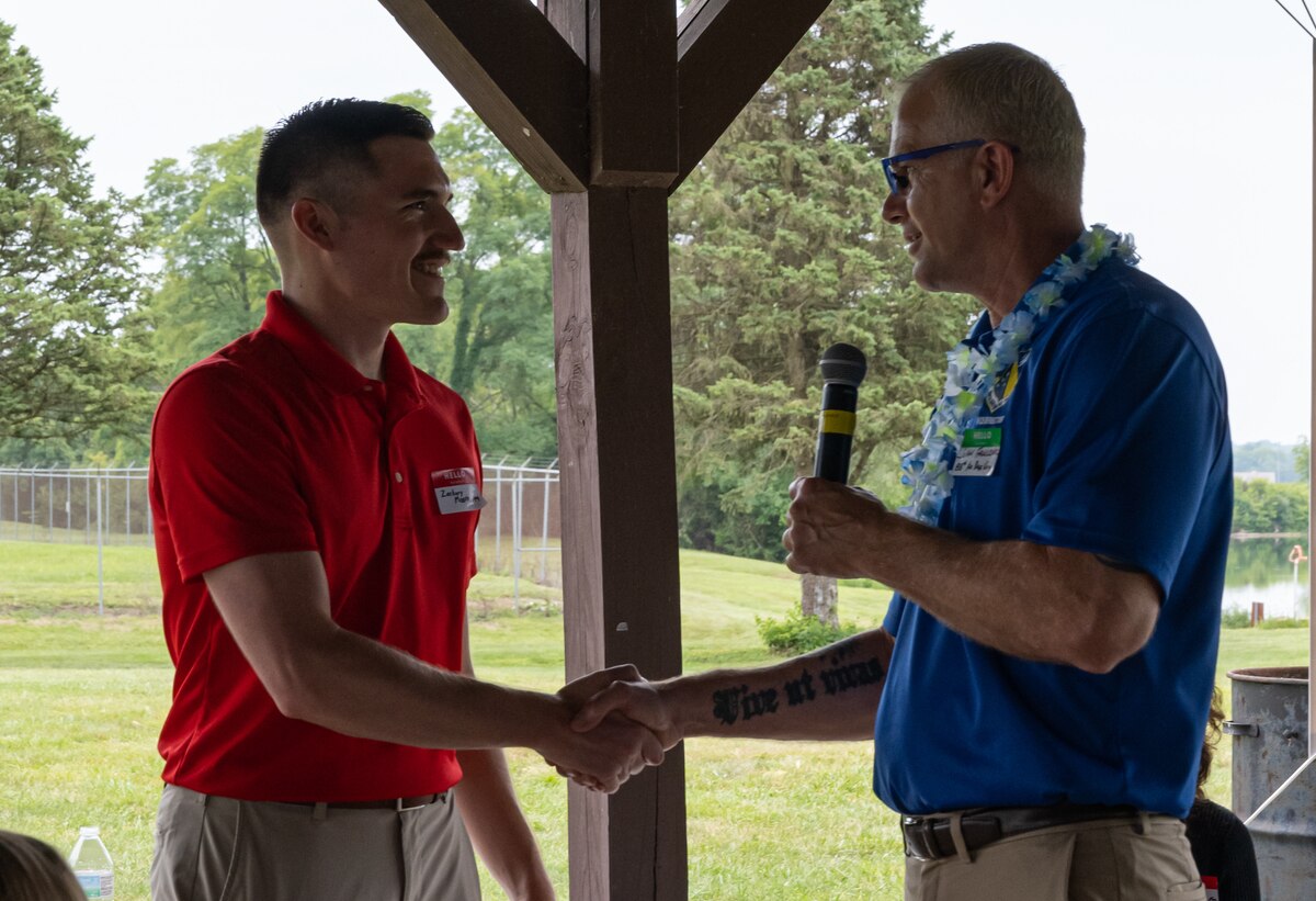 John Faulkner, 88th Air Base Wing vice director coins Zachary Moore under a canopy.