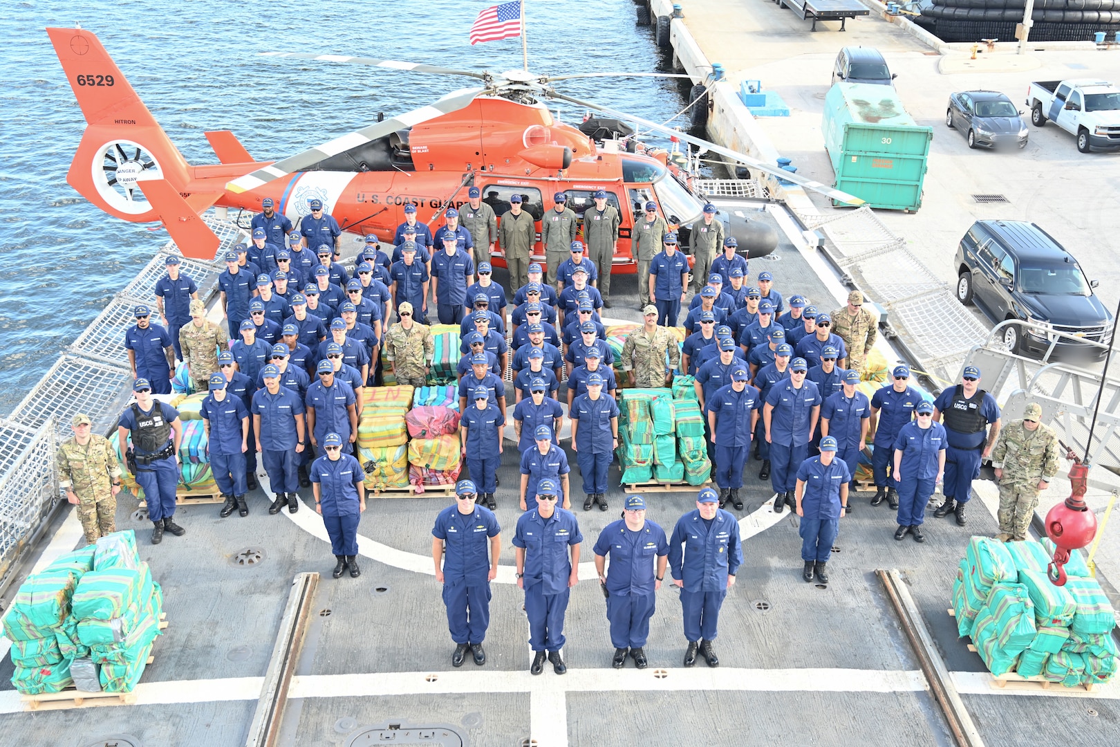 The crew of Coast Guard Cutter Escanaba (WMEC 907) poses for a group photo on the cutter's flight deck during a contraband offload, Aug. 23, 2024, alongside select personnel from Coast Guard Cutters Spencer (WMEC 905), Legare (WMEC 912), Coast Guard Helicopter Interdiction Tactical Squadron, Pacific Area Tactical Law Enforcement Team, and Coast Guard Atlantic Area Command while moored to the pier in Fort Lauderdale, Florida. Escanaba conducted a 46-day counter-drug patrol in the Eastern Pacific Ocean. (U.S. Coast Guard photo by Petty Officer 2nd Class Brandon Hillard)