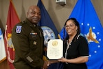 Army general and woman shake hands and hold certificate