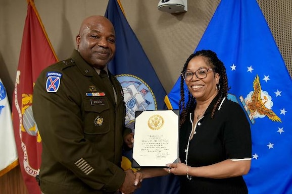 Army general and woman shake hands and hold certificate