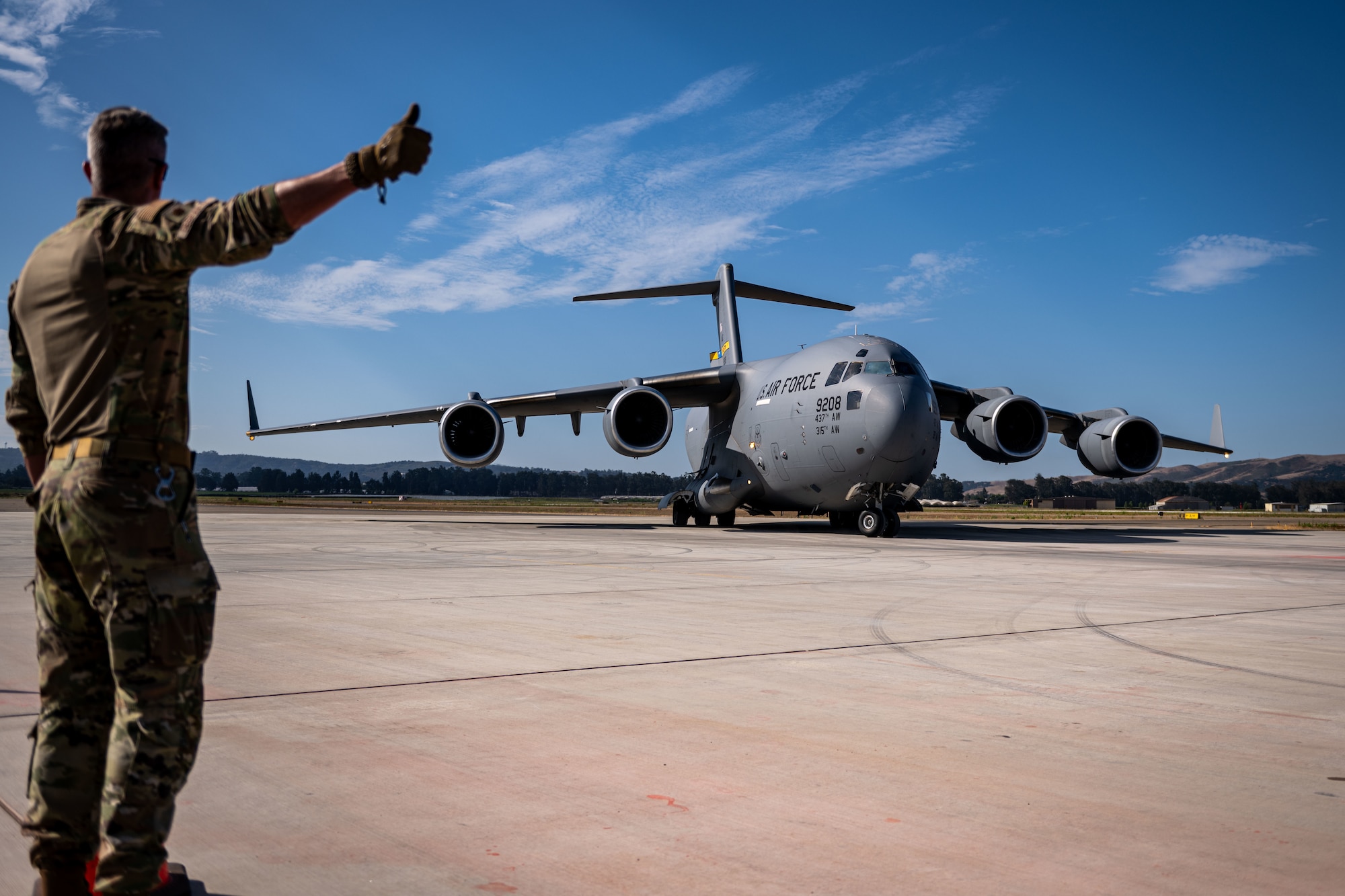 A U.S. Air Force airfield operator marshals a C-17 Globemaster III during Exercise Agile Flag 24-3 at Santa Maria, California, Aug. 2, 2024. AGILE FLAG 24-3 evaluators assessed the 23rd Wing’s ability to deploy to austere locations closer to the forward lines of battle while establishing operational capabilities for agile maneuver, dispersed operations, contested logistics, secure communications, rapid ground refueling and aircraft security measures. (U.S. Air Force photo by 2nd Lt. Benjamin Williams)