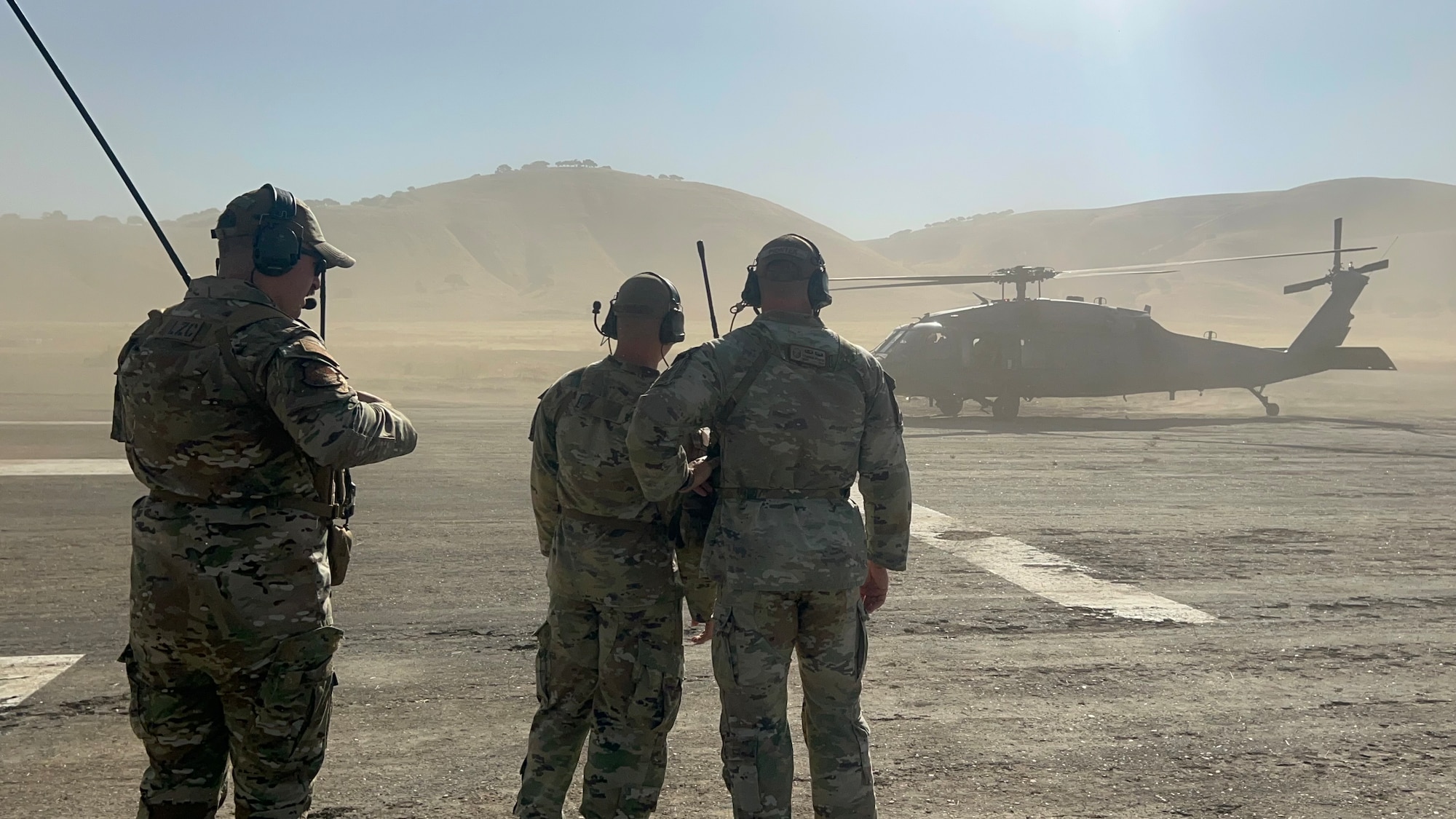 U.S. Air Force Tech. Sgt. David Rost, 9th Operational Support Squadron landing zone controller (left), Master Sgt. Cameron Piontek, 9th OSS landing zone controller, and Staff Sgt. Joseph Hasenauer, 9th OSS landing zone safety officer, from Beale Air Force Base, taxi a pararescue HH-60 Black Hawk from the 129th Rescue Squadron, Moffet Federal Airfield, to park on the Landing Zone at Camp Roberts, California, Aug. 8, 2024.