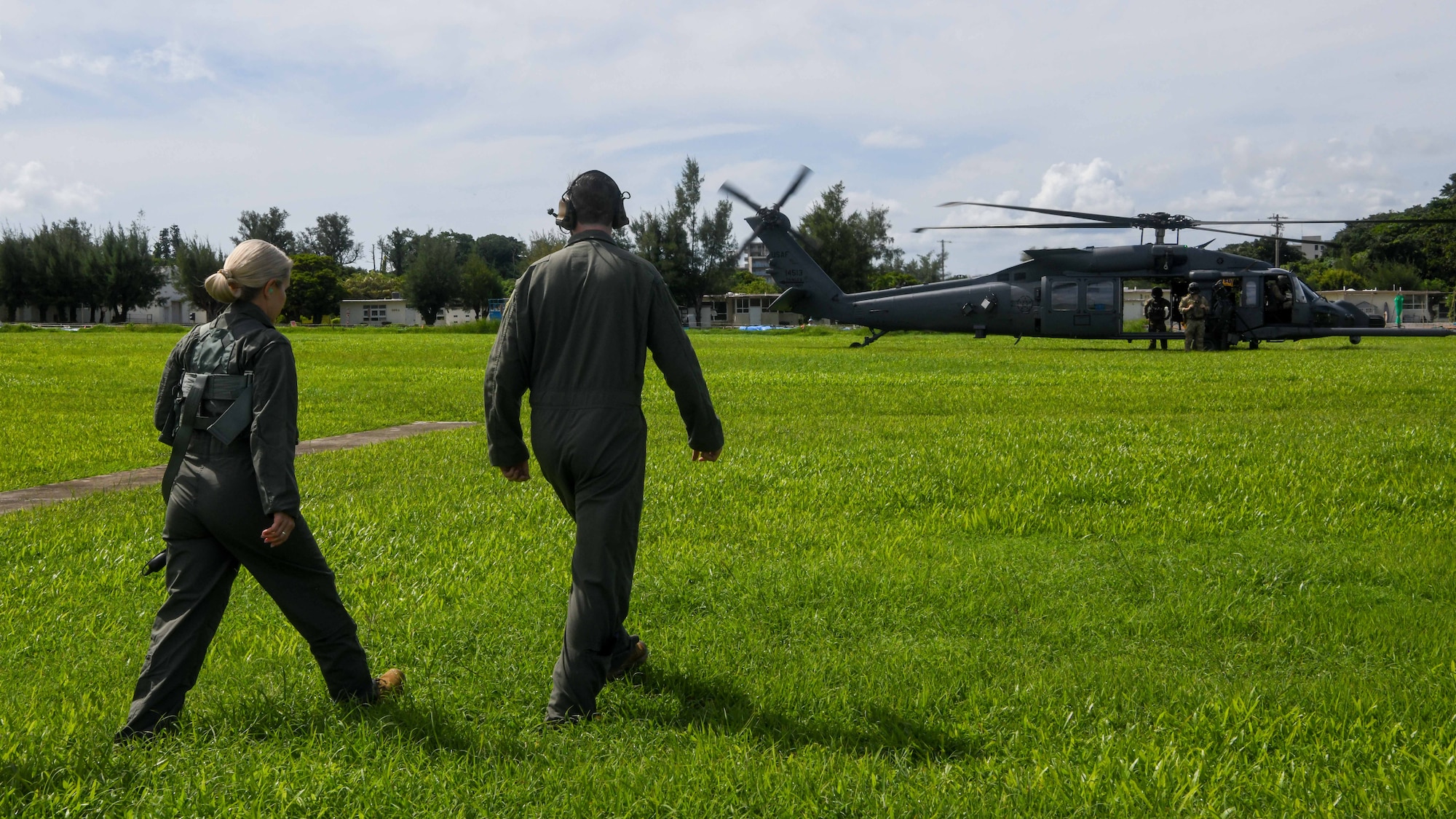 two military memebers walk towards a helicopter