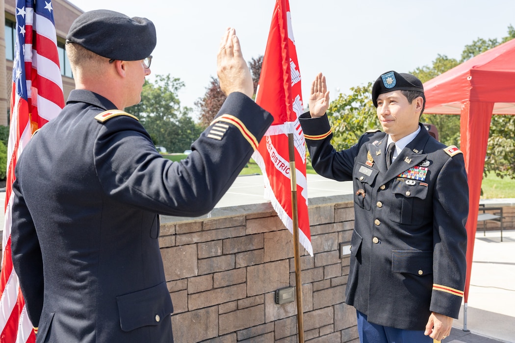 One man in uniform administering the oath of office to another man in uniform.