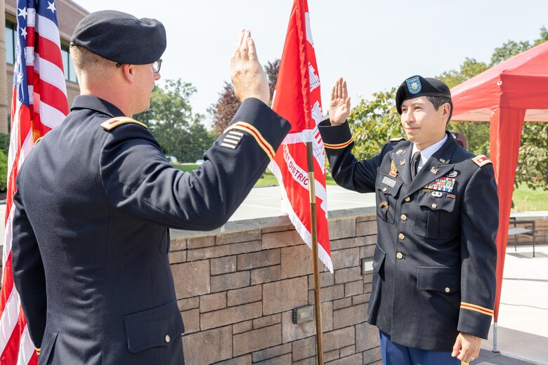 One man in uniform administering the oath of office to another man in uniform.
