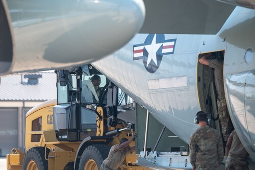 Airmen load a large container into the back of a WC-130J using a forklift