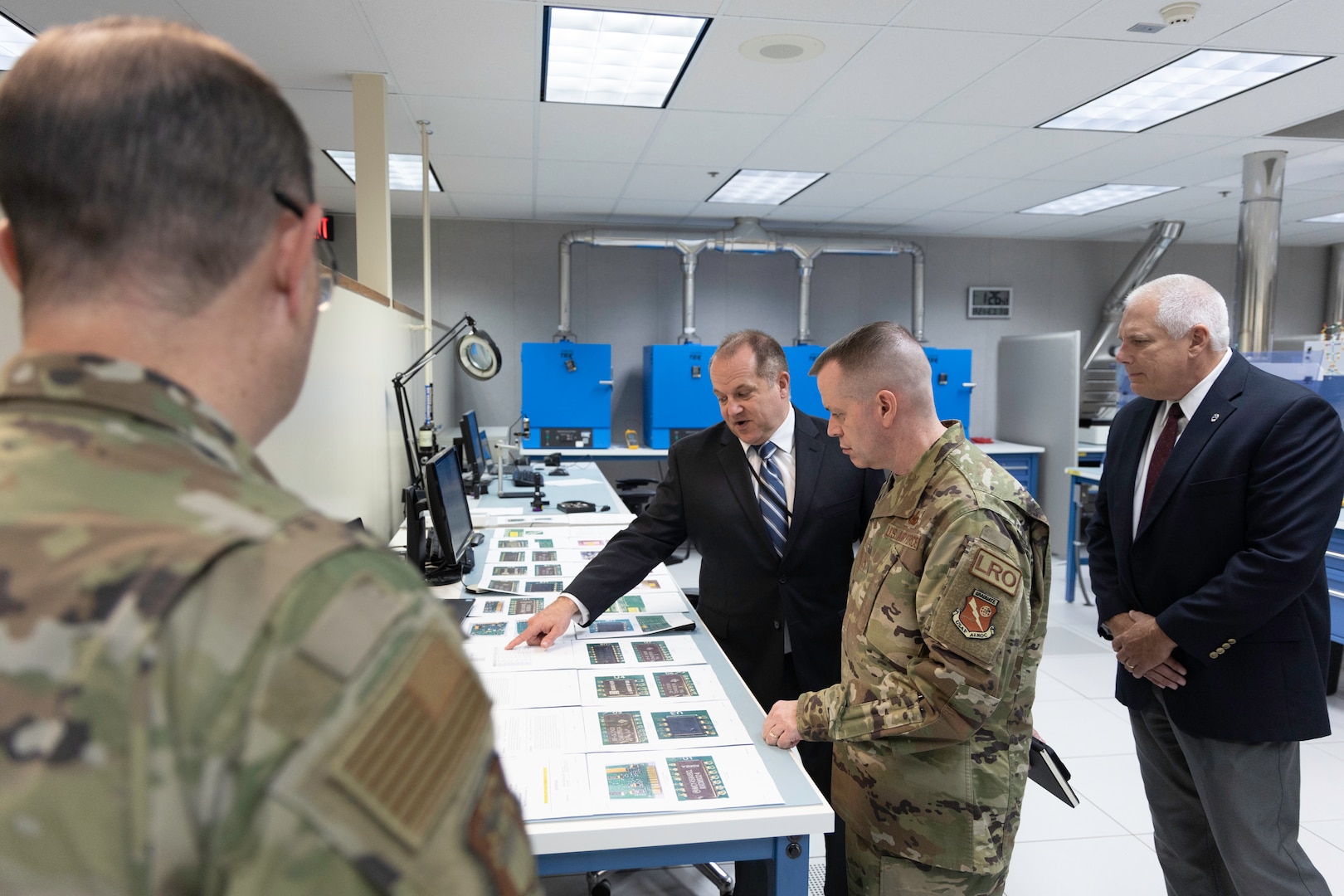Defense Logistics Agency Land and Maritime Electronics Engineer Jeremiah Jones (left) and Product Test Center Chief John Elavsky (right) brief Air Force Maj. Gen. David Sanford (center) about battery lab capabilities during the logistics operations director’s site visit Aug. 21.