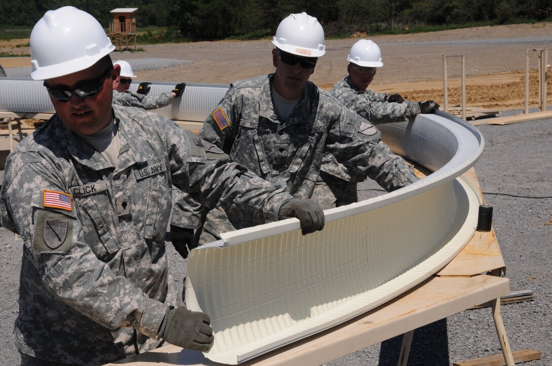 Spc. Roscoe Click, Spc. Matthew Peck and Sgt. Joshua Brown, all of the 149th Vertical Engineer Company, curve steel panels to form a section of a roof for a K-span building at Wendell H. Ford Regional Training Center in Greenville, Ky., Aug. 20, 2012.