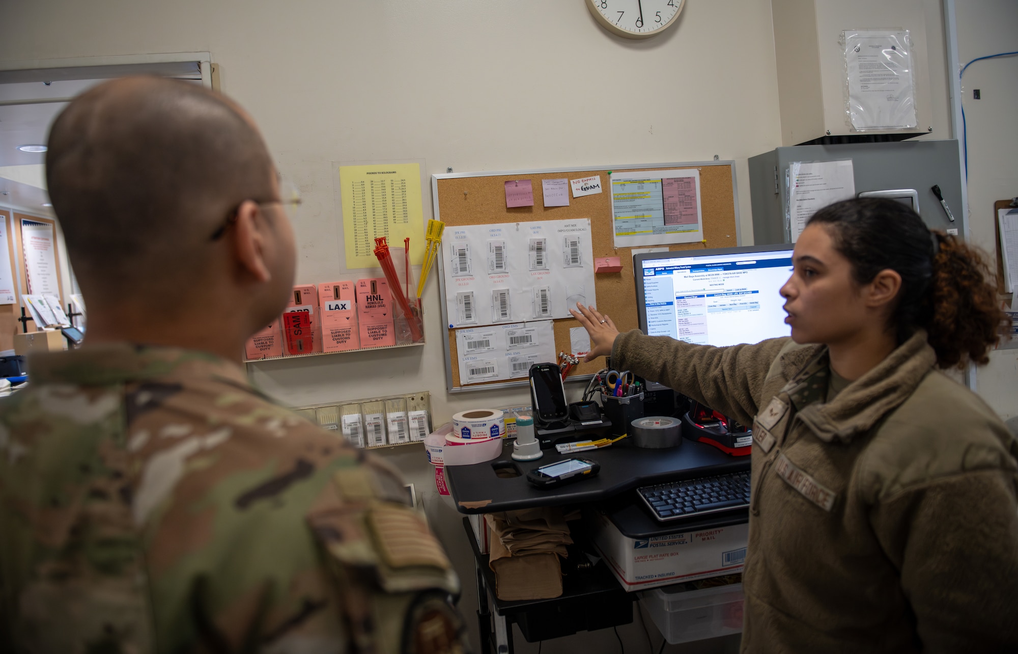 An Airmen points at a display at the outbound mail processing center