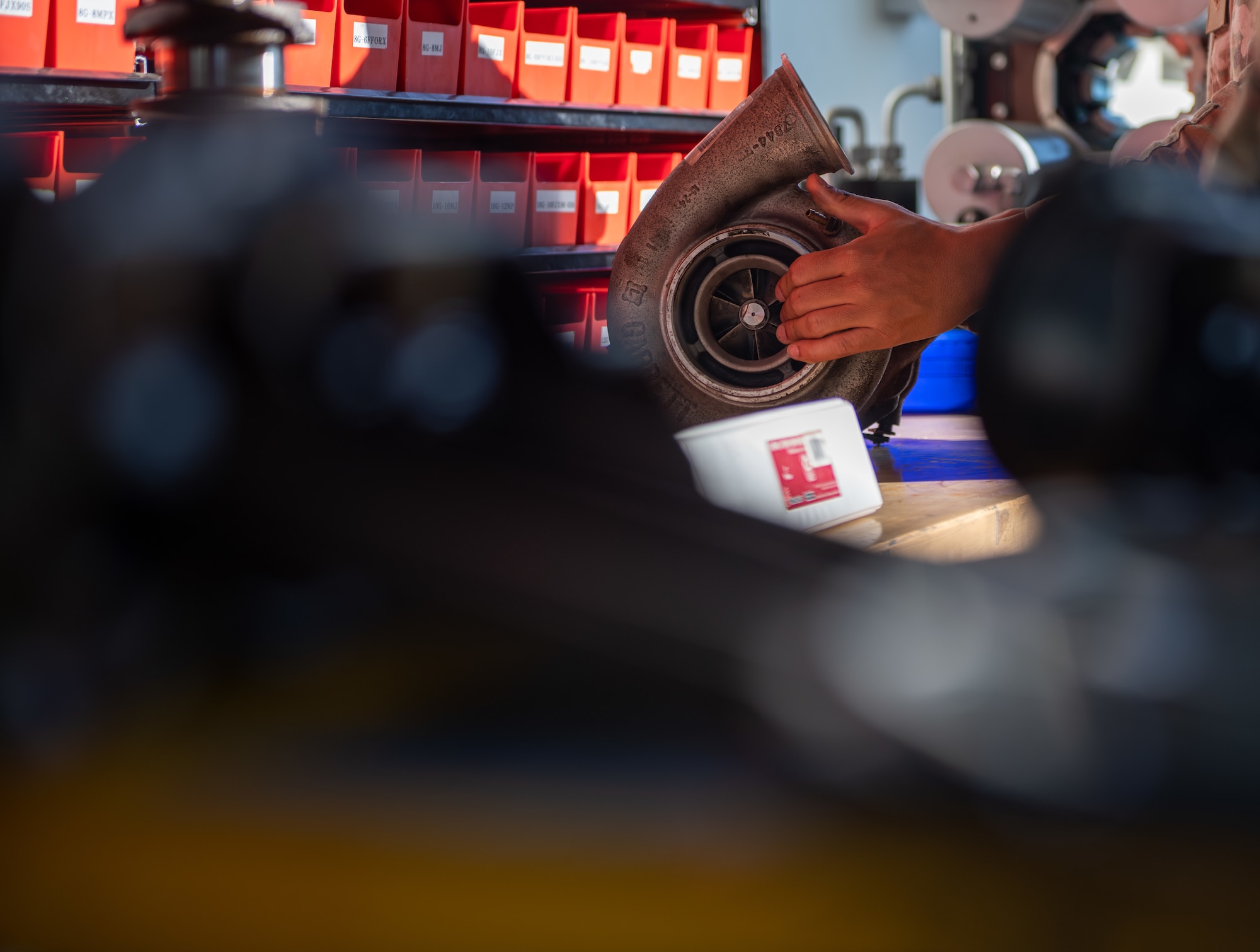 An Airman's hands hold a vehicle engine turbo.