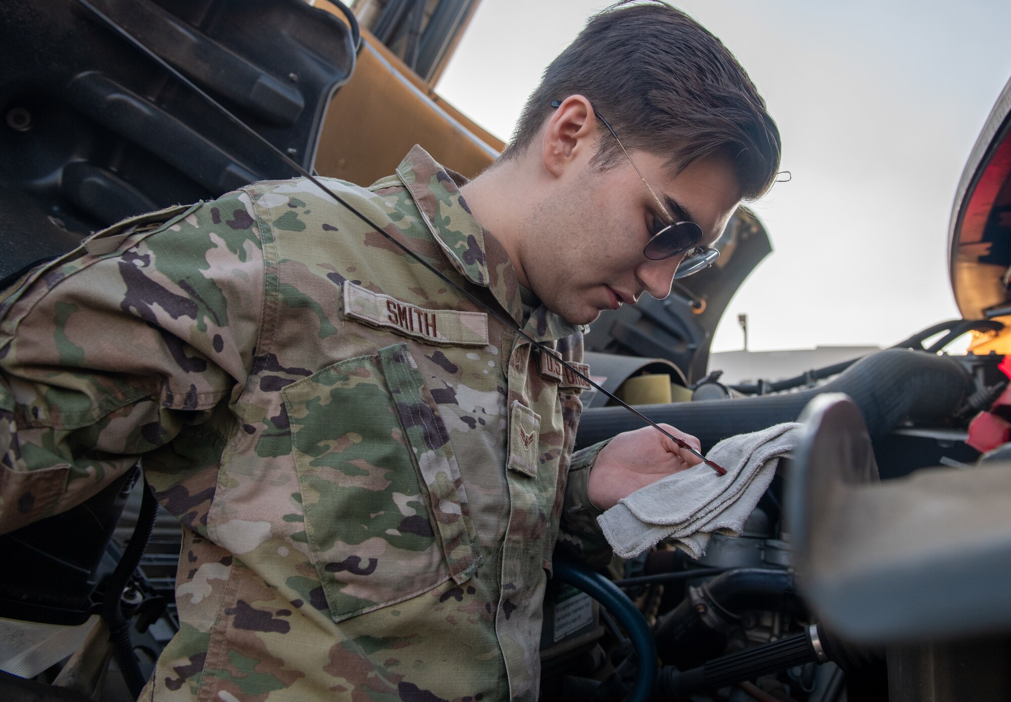 An airmen inspects an oil dipstick when checking the fluid levels on a motor.