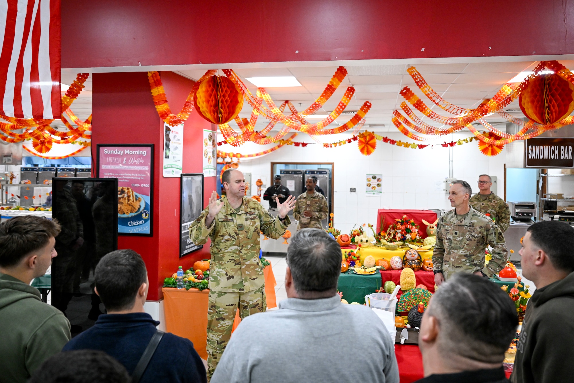 A commander speaks to a group of people before a Thanksgiving meal at the dining facility.