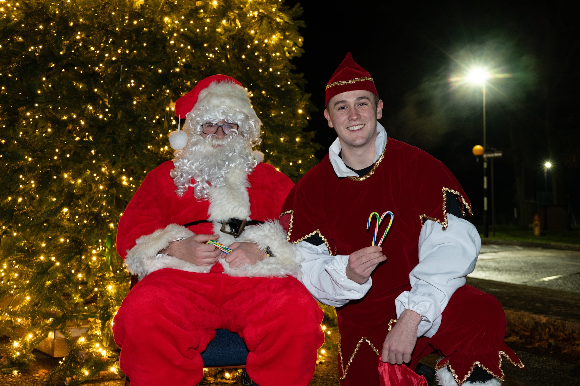 Santa Claus and his elf pose for a photo