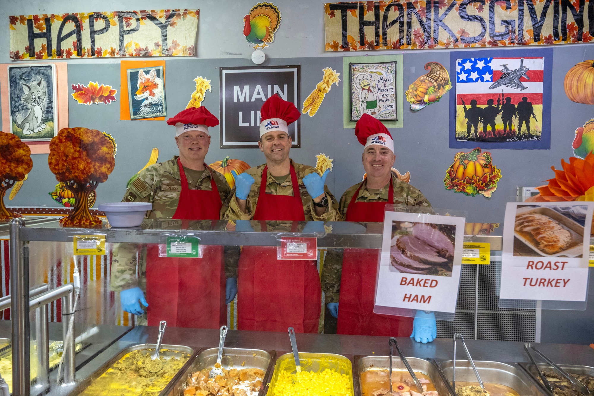 Three Air Force leaders pose for a photo in front of a food service line.